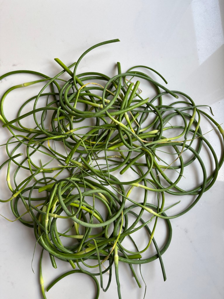 Green garlic scapes chopped on a white countertop.
